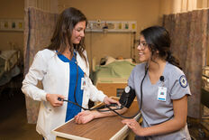 Two female nursing students practicing taking blood pressure readings