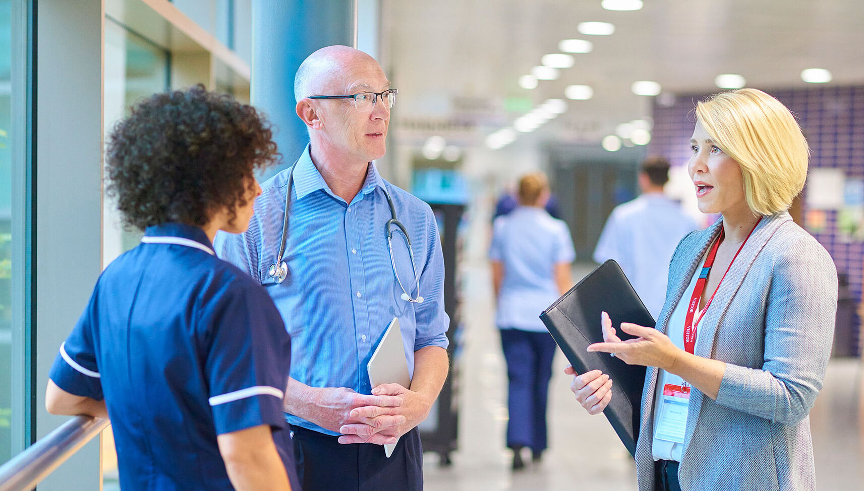 A hospital administrator converses with a doctor and nurse
