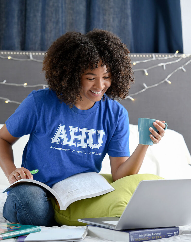 A young female African-American student studying in her dorm room