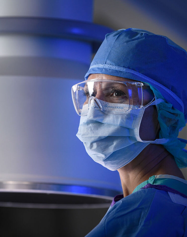 A healthcare worker in a mask and scrubs in an operating room